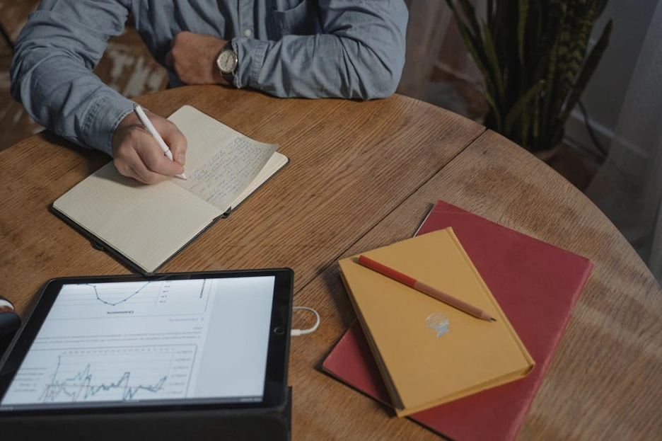 Persona che scrive su un taccuino durante una sessione di coaching.